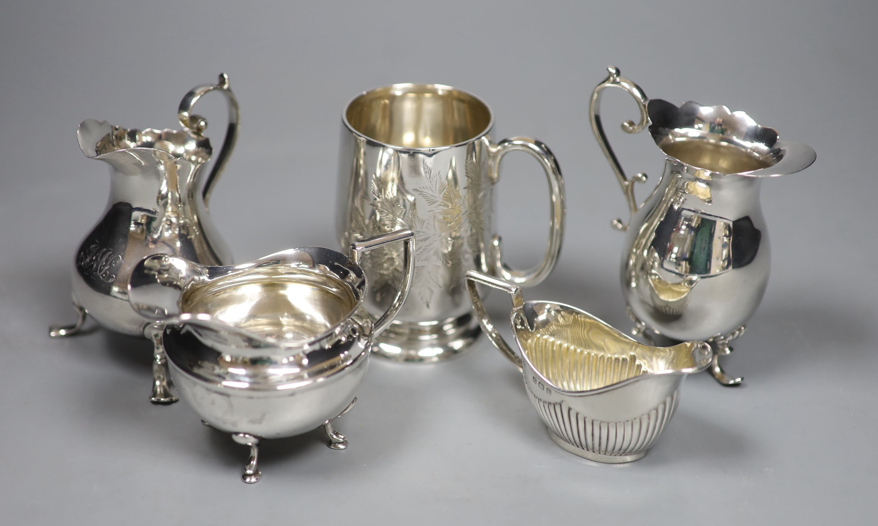 A Victorian engraved silver footed Christening mug and four silver cream jugs, various, 12.3 oz approx